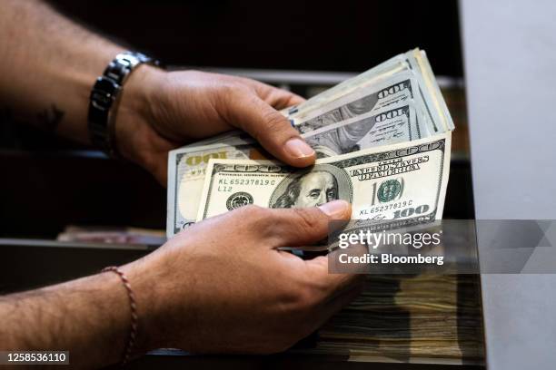 An employee counts US 100 dollar banknotes in Istanbul, Turkey, on Thursday, June 8, 2023. Turkey's lira plunged to a record low as state-run lenders...