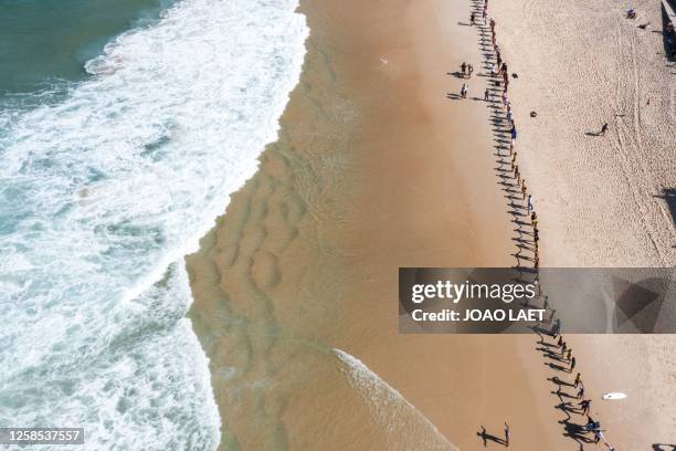 Aerial view of volunteers from a Non-Governmental Organization holding hands after cleaning the Sao Conrado beach in Rio de Janeiro, Brazil on June...