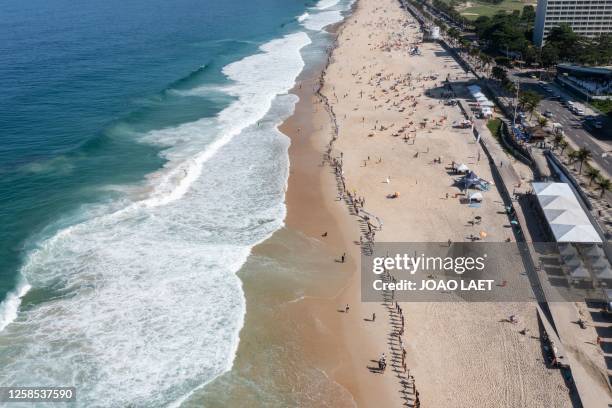 Volunteers from a Non-Governmental Organization hold hands after cleaning the Sao Conrado beach in Rio de Janeiro, Brazil on June 8, 2023 in the...