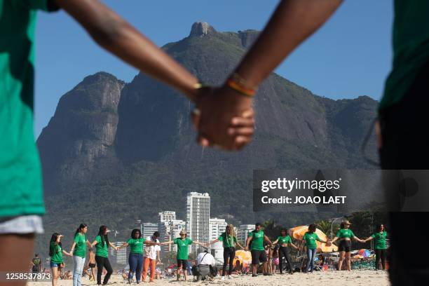 Volunteers from a Non-Governmental Organization hold hands after cleaning the Sao Conrado beach in Rio de Janeiro, Brazil on June 8, 2023 in the...