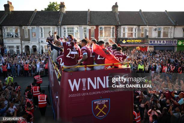 Members of the public gather beneath West Ham United players travelling on an open-top bus, during a parade through the streets of east London on...