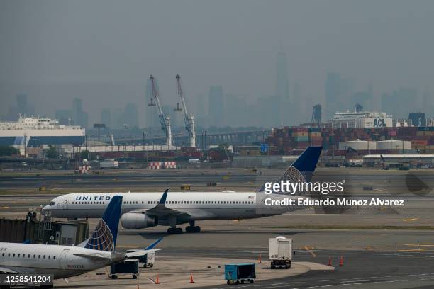 One World Trade Center in New York City is obscured amid hazy conditions due to smoke from the Canadian wildfires as planes sit on the tarmac at...