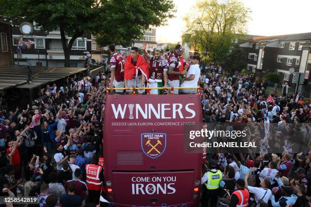 Fans line the route as West Ham United players travel on an open-top bus, during a trophy parade through the streets of east London on June 8 to...