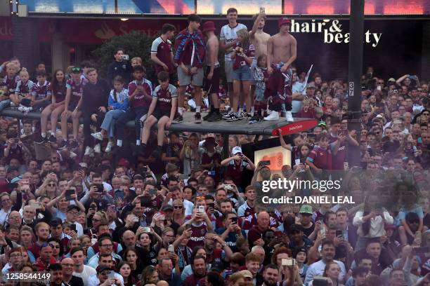 Fans line the route as West Ham United players travel on an open-top bus, during a trophy parade through the streets of east London on June 8 to...