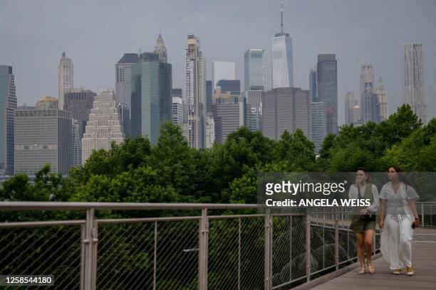 People walk before the skyline of lower Manhattan as smoke from wildfires in Canada cause hazy conditions in New York City on June 8, 2023. Smoke...