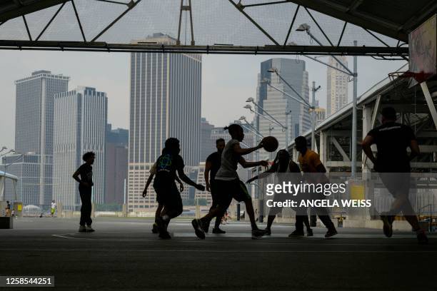 Teenagers play basketball as smoke from wildfires in Canada cause hazy conditions in New York City on June 8, 2023. Smoke from Canadian wildfires...