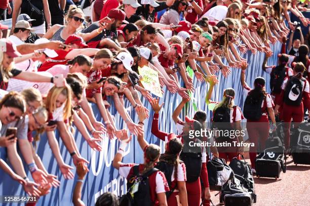 Fans of the Oklahoma Sooners high five players as they enter the stadium before the Division I Women's Softball Championship against the Florida...