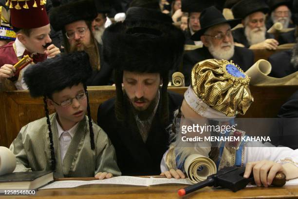 Child listens on as Ultra Orthodox Jews from the Wiznitz Hassidim group reads the Ester scrolls at the synagogue in the Israeli town of Beni Brak...