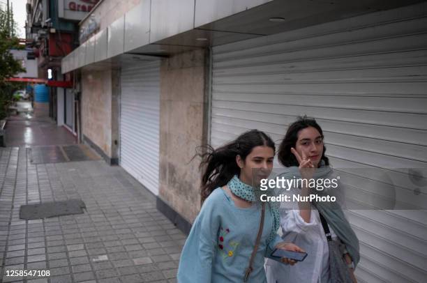 Two Iranian women walk along a street-side in the strong winds without wearing the mandatory Islamic headscarf in downtown Tehran,on June 8, 2023.
