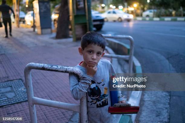 An Iranian child labor looks on as he poses for a photograph on a street-side in downtown Tehran at sunset, after the strong winds and rain,on June...