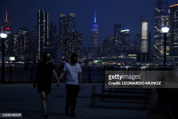 Pedestrians walk along the skyline of midtown Manhattan, New York, as seen from across the Hudson river in Weehawken, New Jersey, on June 8, 2023....