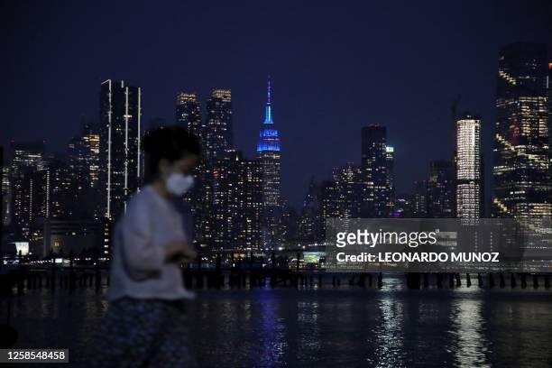 Pedestrian walks along the skyline of midtown Manhattan, New York, as seen from across the Hudson river in Weehawken, New Jersey, on June 8, 2023....