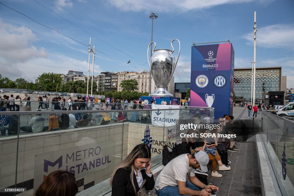 The 2023 UEFA Champions League Giant Trophy Seen Behind People uefa-champions-league-trophy-wallpaper