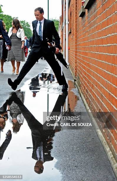 Race-goer is reflected in a puddle of water on Ladies Day at the annual Royal Ascot horse racing event near Windsor, Berkshire on June 16, 2011. The...