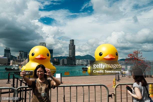 People take photos of the two giant Inflatable Rubber Rucks float on Victoria Harbour during the Double Ducks exhibition on June 9, 2023 in Hong...