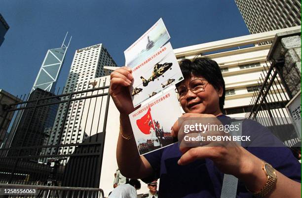 Hong Kong woman shows off souvenir invitation cards 29 September allowing the holder to visit a different People's Liberation Army base in Hong Kong...