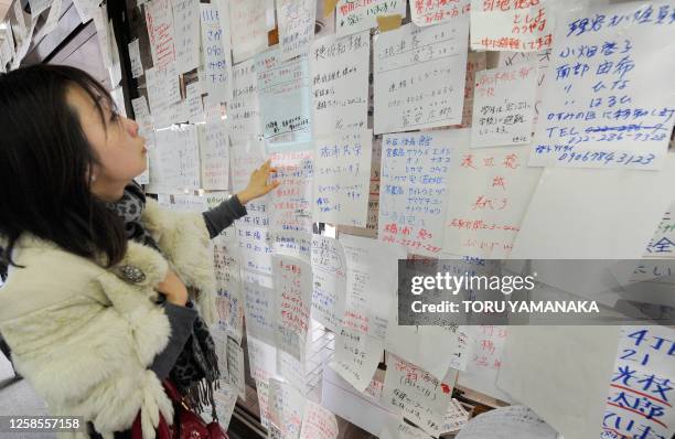 Woman checks messages on the wall at Natori City Hall in Natori, Miyagi Prefecture, on March 14, 2011 following the tsunami and earthquake of March...