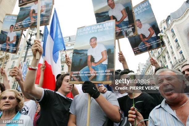 Des personnes brandissent des posters de Ilan Halimi et le drapeau national français lors du rassemblement organisé le 13 juillet 2009 à proximité du...