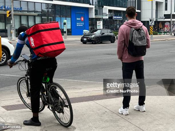Food delivery person waits to cross a street in Toronto, Ontario, Canada, on June 08, 2023. Officials have warned that Some of the worst air quality...