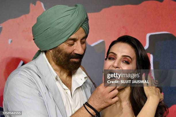 Bollywood actor Sunny Deol feeds actress Ameesha Patel a blackberry during the trailer launch event of their upcoming Indian Hindi-language romantic...