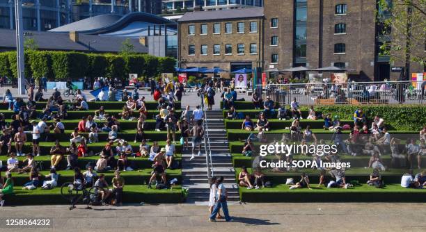 People enjoy the sunshine on the artificial turf next to Regent's Canal in Granary Square, King's Cross, as temperatures soar in the capital.