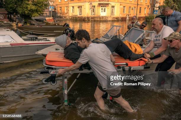 Volunteers and others push a stretcher carrying an elderly person who was evacuated from a flooded area on June 9, 2023 in Kherson, Ukraine. Early...