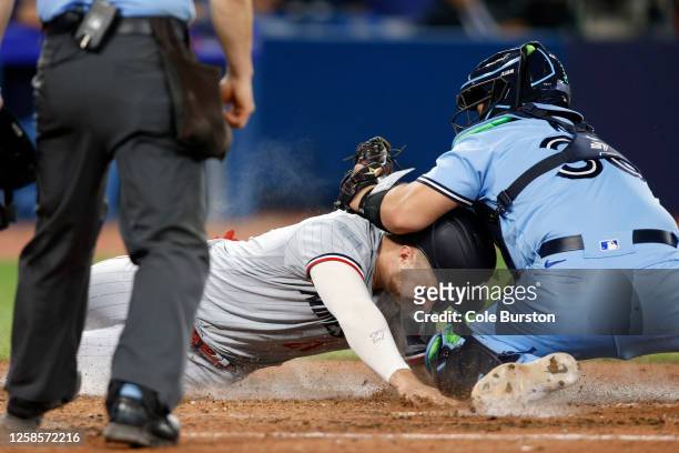 Ryan Jeffers of the Minnesota Twins scores at home off a sacrifice hit from Michael A. Taylor as Alejandro Kirk of the Toronto Blue Jays comes in...