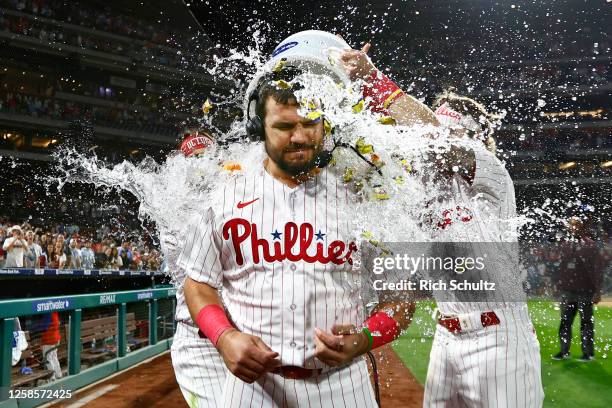 Kyle Schwarber of the Philadelphia Phillies is doused with water by teammates Brandon Marsh and Bryson Stott after hitting a walkoff homer against...