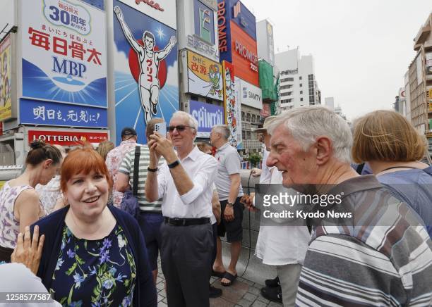 Tourists from Britain walk in Osaka's Dotonbori area on June 10 as the number of travelers to Japan has been recovering sharply following the lifting...