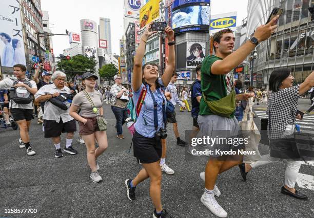 Tourists from the United States cross the famous scramble intersection in Tokyo's Shibuya area on June 10 as the number of travelers to Japan has...