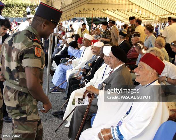 Un soldat français du 21e Régiment d'infanterie de marine discute avec un vétéran du débarquement de Provence, le 15 août 2004 au Cap de Dramont à...