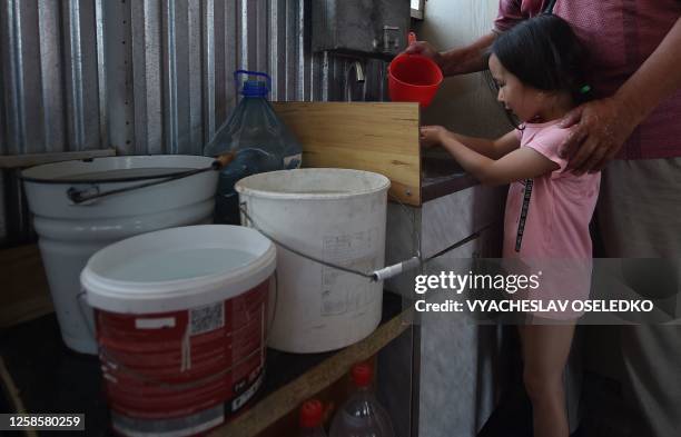 Man pours water from a bucket to wash the hands of a girl in his house in the Archa-Beshik district in the capital Bishkek on June 8, 2023. Residents...