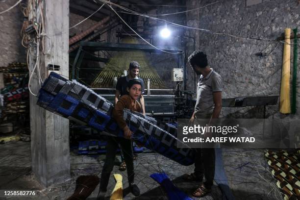 In this picture taken on June 1 a child and men work at a factory making mats and rugs from recycled plastic, in Sarmada in Syria's northwestern...