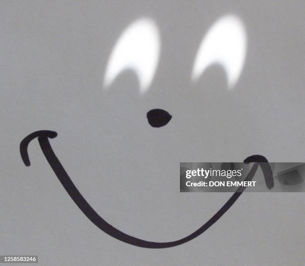Pair of pinhole projected images of the partial Solar Eclipse are projected on to a piece of paper to form what looks like eyes on a happy face 25...