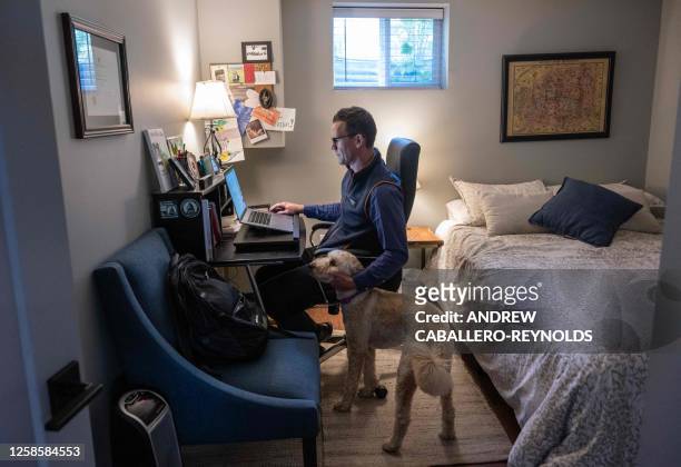 Danny Crouch pets his dog as he sits in his basement working from home in Arlington, Virginia, on May 25, 2023. The pandemic forced Americans to work...