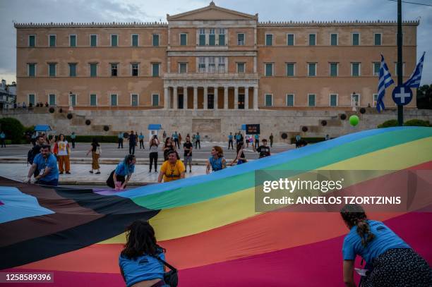 Participants hold a giant rainbow colored flag in front of the Greek parliament during the Athens Pride parade in Athens on June 10, 2023.
