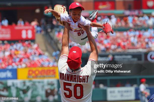 Adam Wainwright of the St. Louis Cardinals holds his son Caleb up after Claeb threw out a ceremonial first pitch prior to playing against the...