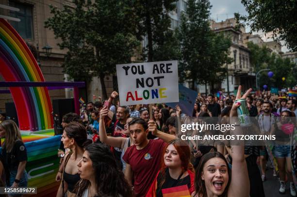 Participant holds a placard reading "You are not alone" during the Athens Pride parade in Athens on June 10, 2023.