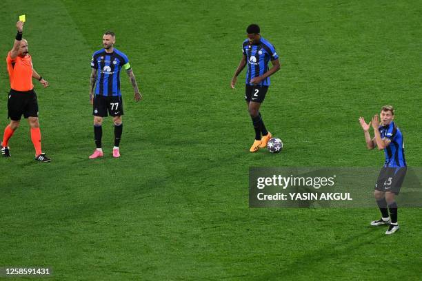 Polish referee Szymon Marciniak gives a yellow card to Inter Milan's Italian midfielder Nicolo Barella during the UEFA Champions League final...