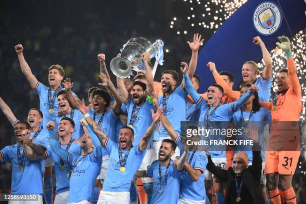 Manchester City's German midfielder Ilkay Gundogan lifts the European Cup trophy as they celebrate on the podium after winning the UEFA Champions...