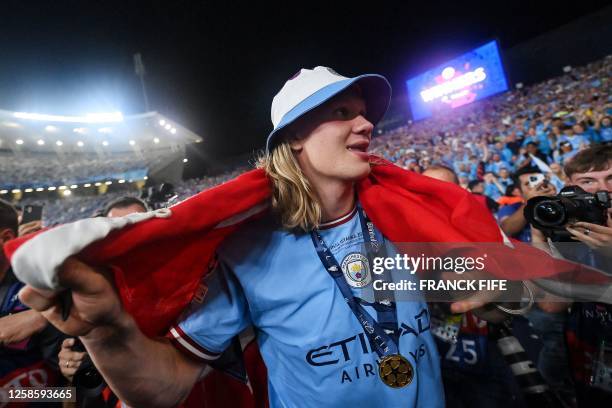 Manchester City's Norwegian striker Erling Haaland, wrapped in the Norwegian flag, celebrates with the fans after winning the UEFA Champions League...