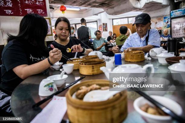 This picture taken on June 8 shows people eating Yum Cha, Cantonese brunch involving tea and dim sum, at a restaurant in Hong Kong. The circular...