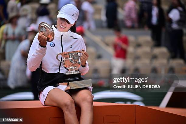 Poland's Iga Swiatek checks the top of the trophy Suzanne Lenglen as she poses following her victory over Czech Republic's Karolina Muchova during...