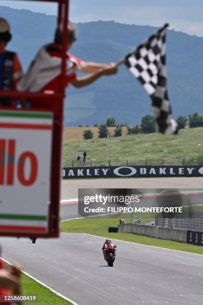 Ducati Italian rider Francesco Bagnaia crosses the finish line to win the race as a checkered flag is waved during the Italian MotoGP race at Mugello...