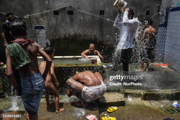 People are bathing on the road side on a hot and humid day in Kolkata, India on 11 June 2023.