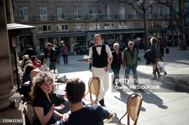 People sit a a cafe terrace on March 15, 2012 in Paris, as the temperatures rose to 20 degrees in the French capital. AFP PHOTO / FRED DUFOUR