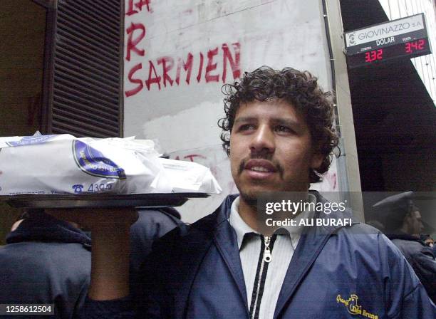 Waiter is seen in action behind a sign posting the current exchange rate in Buenos Aires, Argentina 22, May 2002. Un mozo con su bandeja de comida...