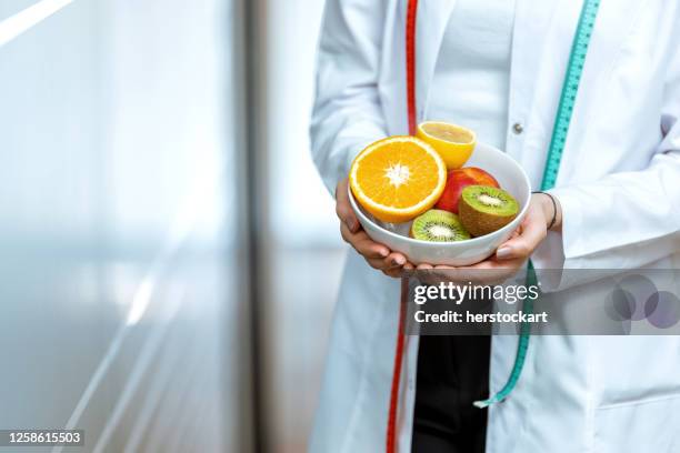 weibliche ernährungsberaterarzt hände halten früchte - ernährungsberatung stock-fotos und bilder