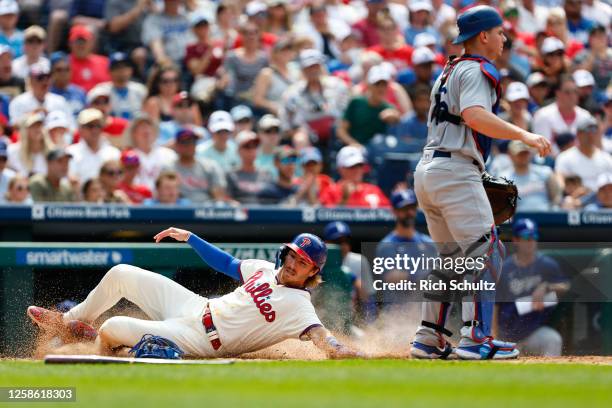 Bryson Stott of the Philadelphia Phillies slides safely past catcher Will Smith of the Los Angeles Dodgers as he scores on a single by Kody Clemens...