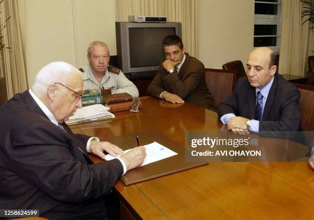 Israeli Prime Minister Ariel Sharon signs the order for the evacuation of settlers from the Gaza Strip while Defense Minister Shaul Mofaz looks at...